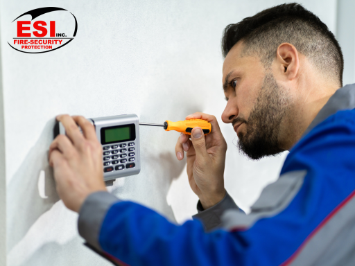 a man using a screwdriver to fix a security system access control systems